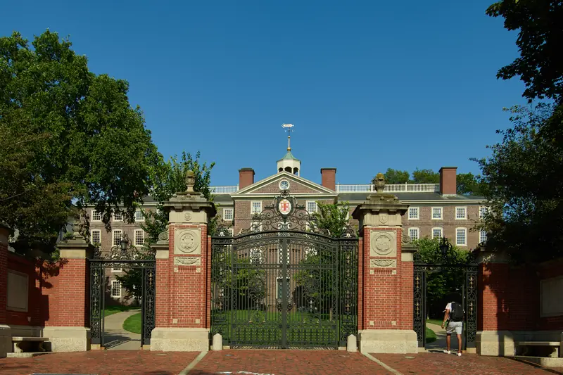 The Van Wickle Gates at Brown University in Providence, Rhode Island, with University Hall behind them under a deep blue sky.