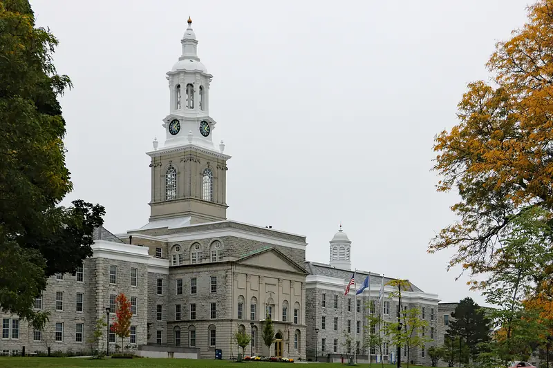 The clock tower of Hayes Hall at the University at Buffalo, among trees in fall color.