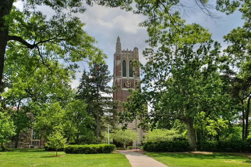 Beaumont Tower at Michigan State University in East Lansing, framed by green trees.