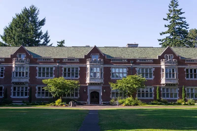 Eliot Hall at Reed College in Portland, Oregon: red brick and pale stone behind a wide lawn, with tall firs on either side.
