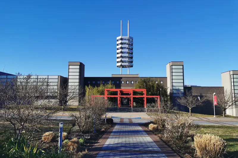The Charles B. Wang Center at Stony Brook University: a red gateway and a tiered tower under a clear blue sky.